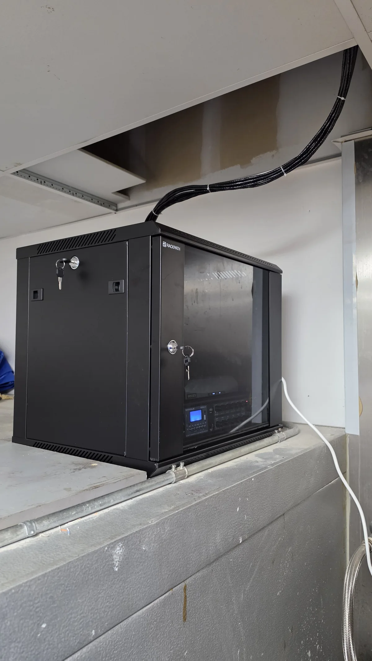Wall-mounted communications cabinet with enclosed network equipment