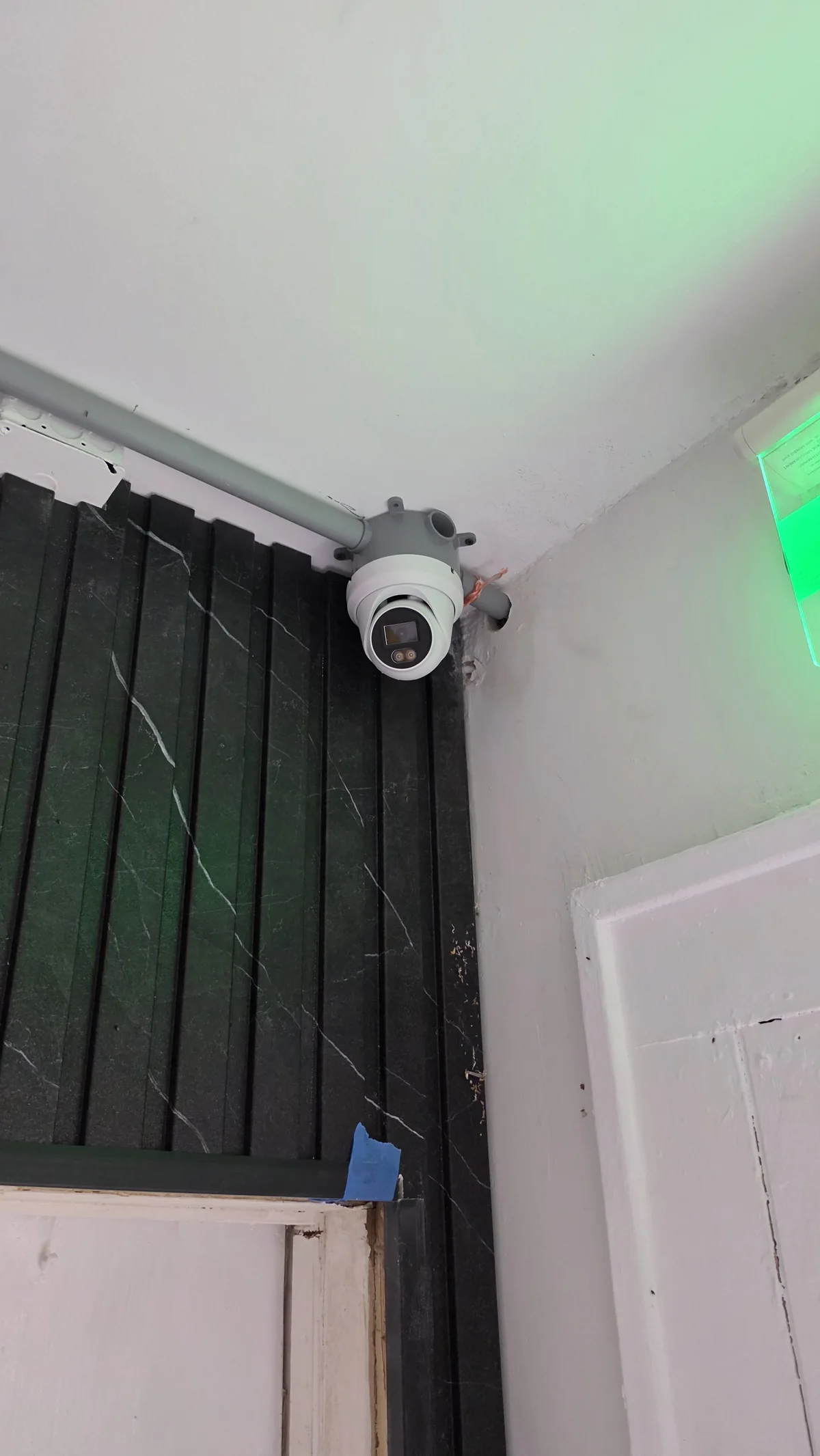 Indoor dome security camera near a building doorway