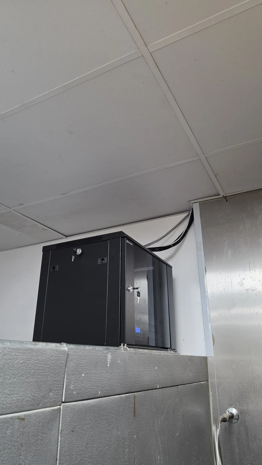 A wall-mounted network cabinet illustrates the need to plan access, cable entry, and usable installation space.